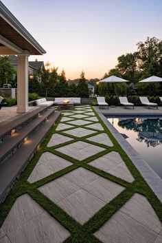 an outdoor swimming pool with grass growing on the walkway and lawn chairs in the background