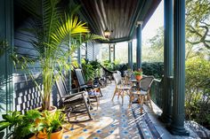 a porch with chairs and potted plants on it