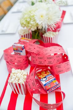 red and white striped table cloth with popcorn, candy bar wrappers and flowers on it