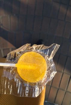 a yellow lollipop sitting on top of a plastic wrapper