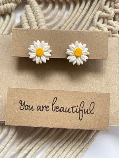 two white and yellow flowers are sitting on top of a card that says you are beautiful