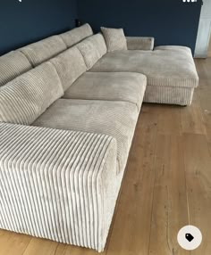 a couch that is sitting on top of a hard wood floor in front of a blue wall