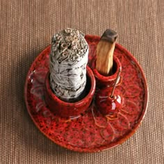 a red plate with two small bottles and a wooden stick in it on a brown mat