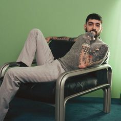 a man with tattoos sitting in a chair