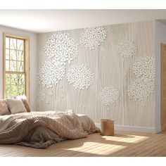 a bed sitting under a window next to a wall covered in white flowers and leaves