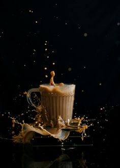 a glass filled with liquid on top of a black table next to some orange peels