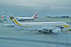 two airplanes are parked on the tarmac at an airport, one is yellow and blue