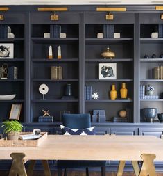 a dining room with blue bookcases and wooden table in front of the bookshelves