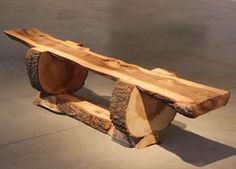 a wooden bench made out of logs on concrete