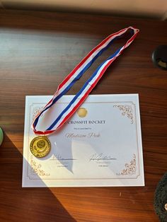 a gold medal is on top of a white paper with a red, blue and yellow ribbon