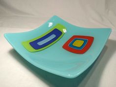 a blue plate with colorful shapes on the top and bottom, sitting on a white surface