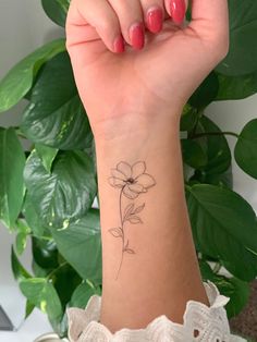 a woman's wrist with a small flower tattoo on the left side of her arm