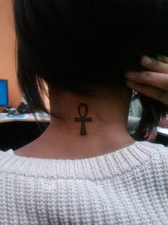 a woman with a tattoo on her neck is looking at the camera and she has an egyptian cross behind her ear