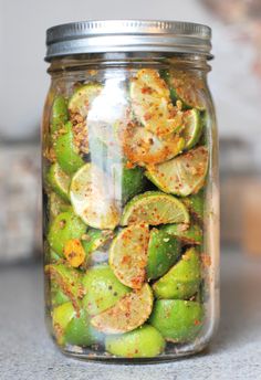 a glass jar filled with sliced up limes and seasoning sitting on top of a counter