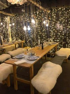 a dining room with lights on the wall and white sheepskin chairs at the table