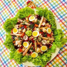 a large salad with hard boiled eggs and vegetables on it sitting on a table cloth