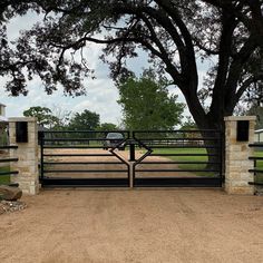 a car is parked in front of a gate at the end of a dirt road