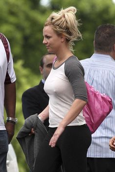 a woman is walking down the street with her hand in her pocket and other people behind her