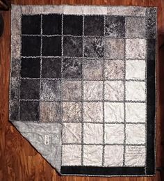 a black and white patchwork rug on a wooden floor