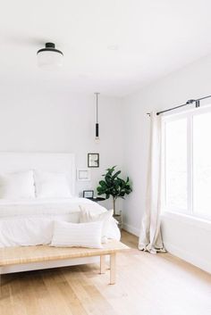 a white bed sitting in a bedroom next to a wooden table and window sill