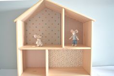 two little mice are sitting on top of a doll house shelf with polka dot wallpaper