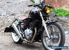 a black motorcycle parked on the side of a road next to a pile of rocks