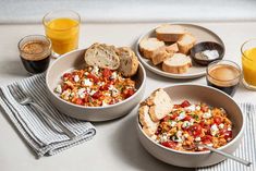 three bowls filled with food on top of a table next to glasses of orange juice