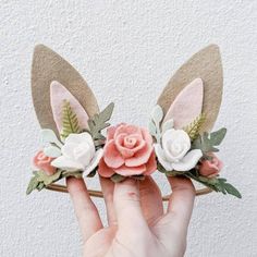 a person holding up some fake flowers in their hands with the ears of two bunny ears