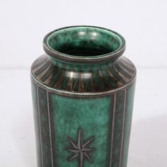 a large green vase with a star on the front and bottom, sitting on a white surface