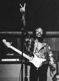 a black and white photo of a man holding a guitar in front of a microphone