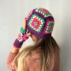 a woman wearing a crocheted hat and mittens with her hair in the wind