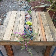 a table made out of pallet wood with flowers on it and plants growing from the top