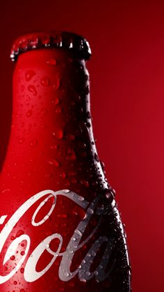 a close up of a coca cola bottle on a red background