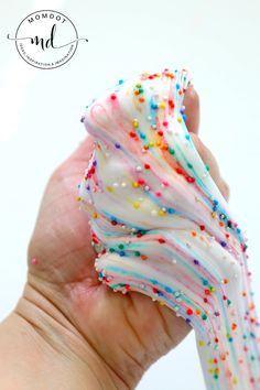 a hand holding a white frosted donut with sprinkles