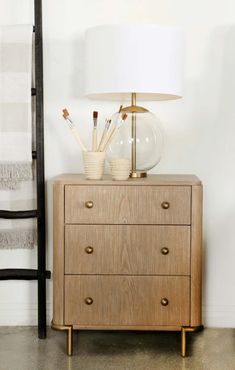 a wooden dresser with two drawers and a lamp on top