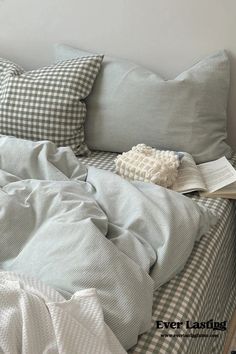 an unmade bed with white and black checkered comforter, pillows and blankets