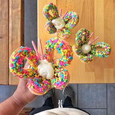 a person holding up donuts with sprinkles on them