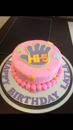 a birthday cake with pink frosting and purple icing is on a black table