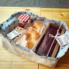 a basket filled with lots of different types of bread and pastries on top of a wooden table