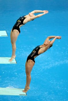 two women diving in the water on their own legs and arms, both wearing black swimsuits