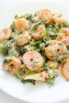 a white plate topped with shrimp and broccoli covered in parmesan cheese