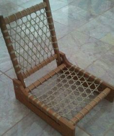 a chair made out of wood and rope sitting on the floor in front of a tiled floor