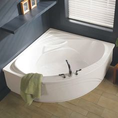 a bathroom with a large white bathtub next to a window