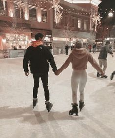 a man and woman are ice skating on the rink at night time, holding hands