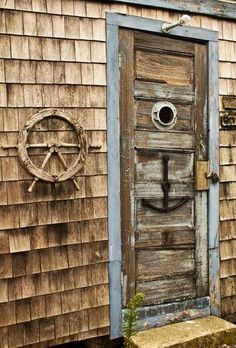 an old wooden door is open on the side of a building with a steering wheel