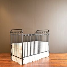 two cribs sitting on top of a hard wood floor next to a wall