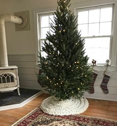 a christmas tree in a room with a rug on the floor and a window behind it