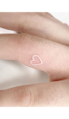 two fingers with small white hearts on the tip of each finger and one has a heart painted on it