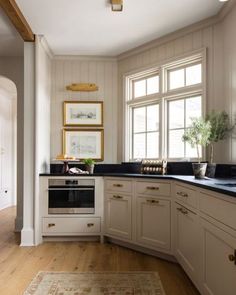 a kitchen with white cabinets and black counter tops next to a rug on the floor