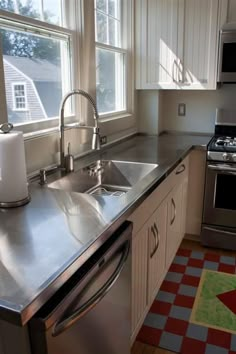 a kitchen with stainless steel appliances and checkered area rug in front of the sink